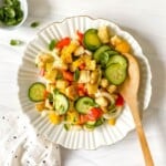panzanella on a white fluted plate with a gold rim next to a spotty cloth.