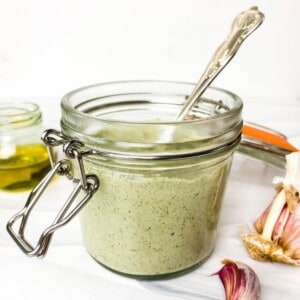 pumpkin seed dressing in a glass jar with a spoon in it.