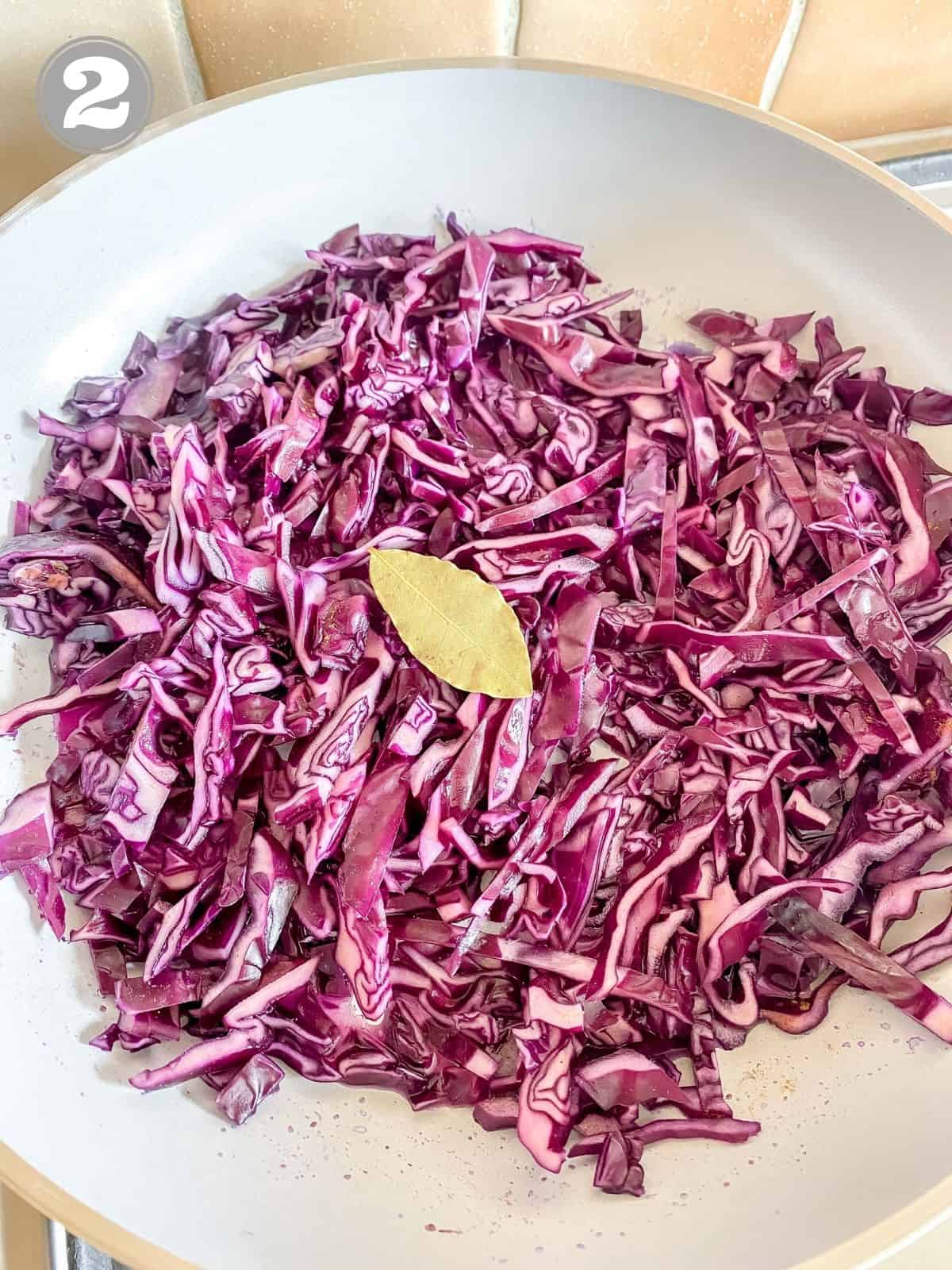 red cabbage and a bay leaf in a grey skillet.