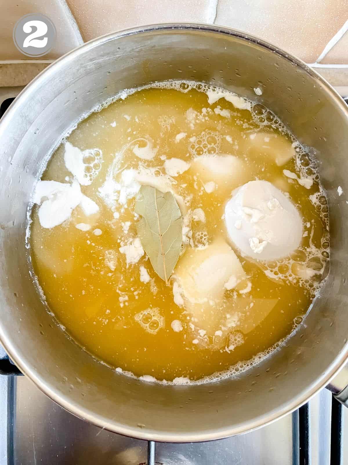 coconut milk, bay leaf, rice and vegetable stock in a pot.
