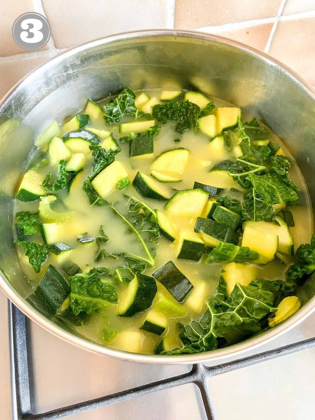 zucchini and cabbage in vegetable broth in a pot.
