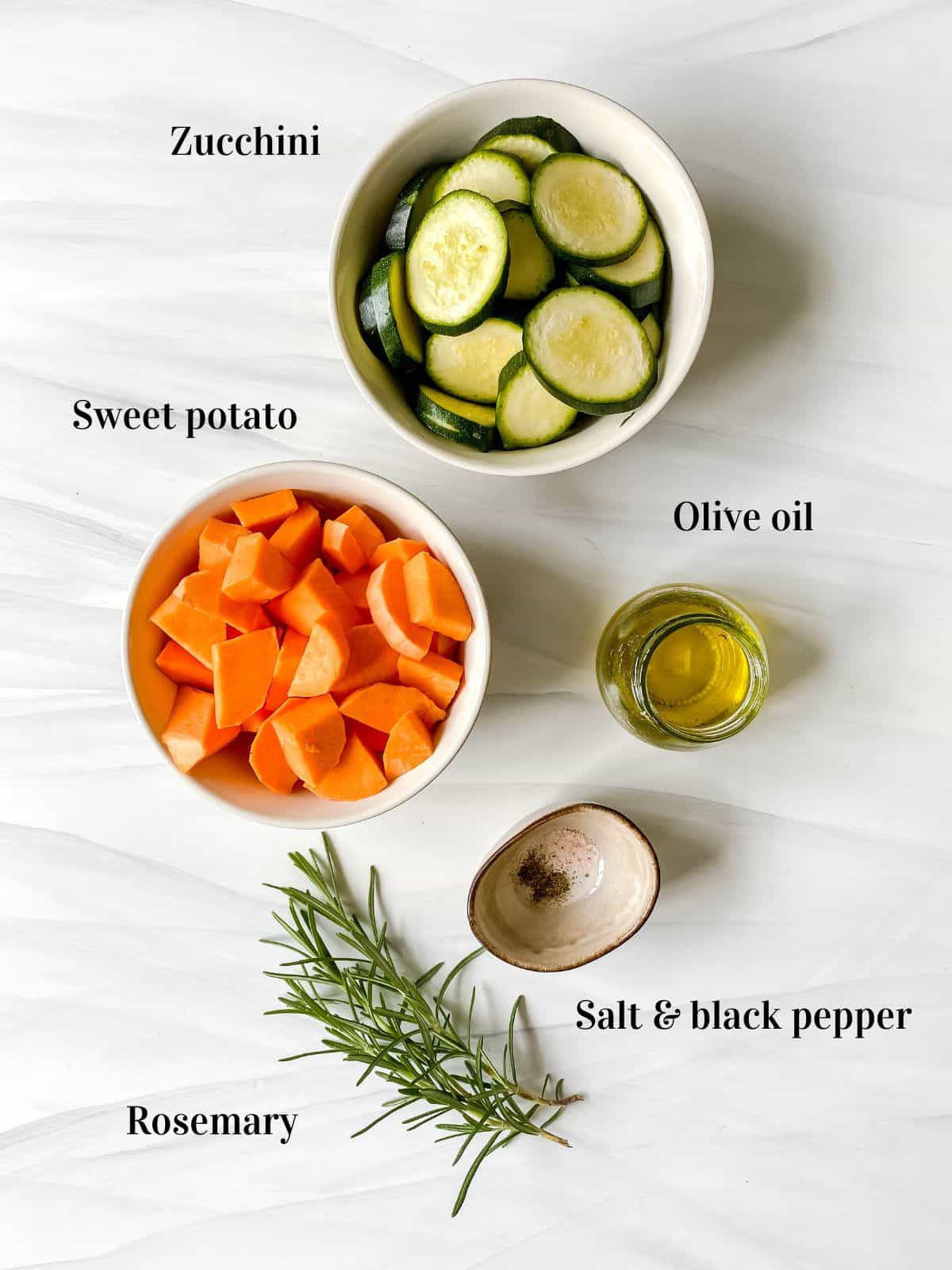 labelled small bowls of sweet potato, zucchini, olive oil, salt and black pepper and sprigs of rosemary.