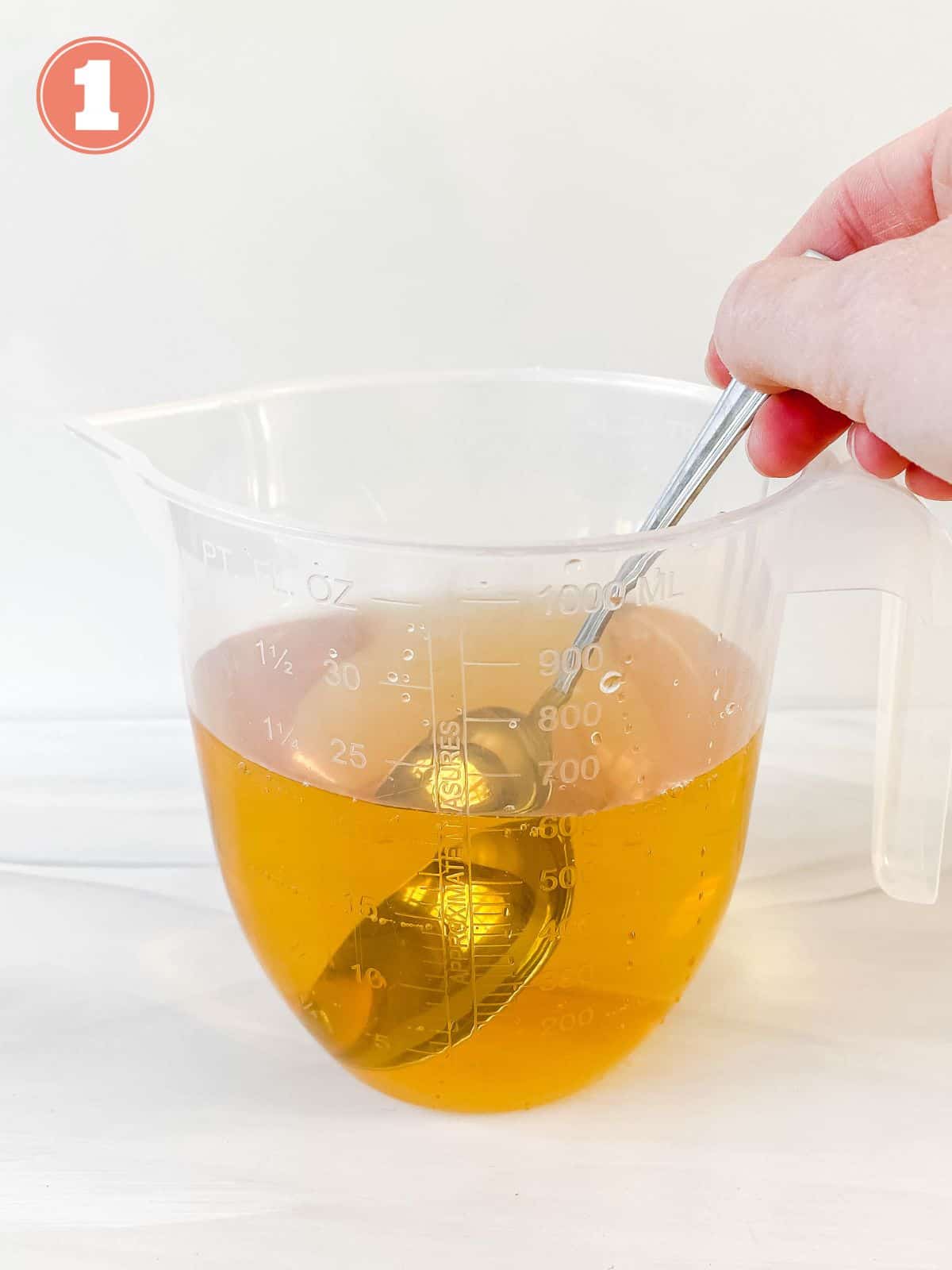 apple juice in a jar being stirred with a spoon.