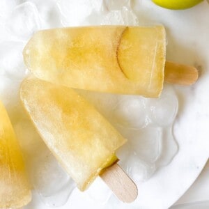 apple juice popsicles on ice next to an apple.