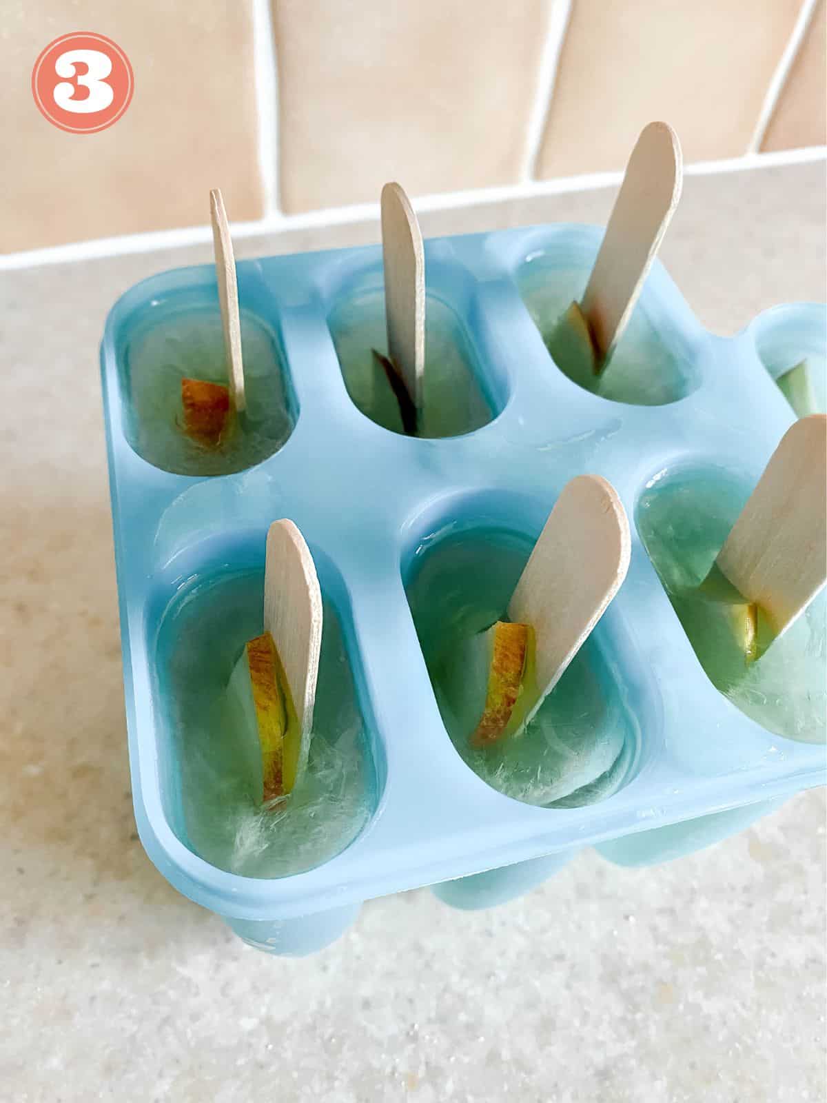 apple juice popsicles in a blue mold.