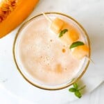 cantaloupe melon in a glass next to a slice of melon.