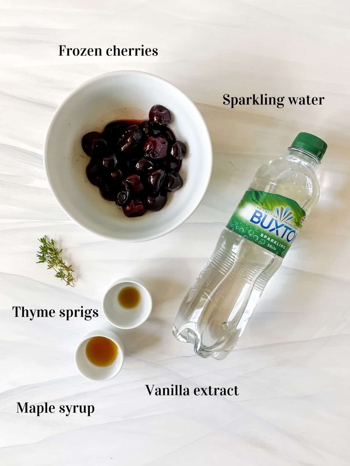 a labelled bowl of frozen cherries, bottle of sparkling water, thyme sprigs and small bowls of maple syrup and vanilla extract.