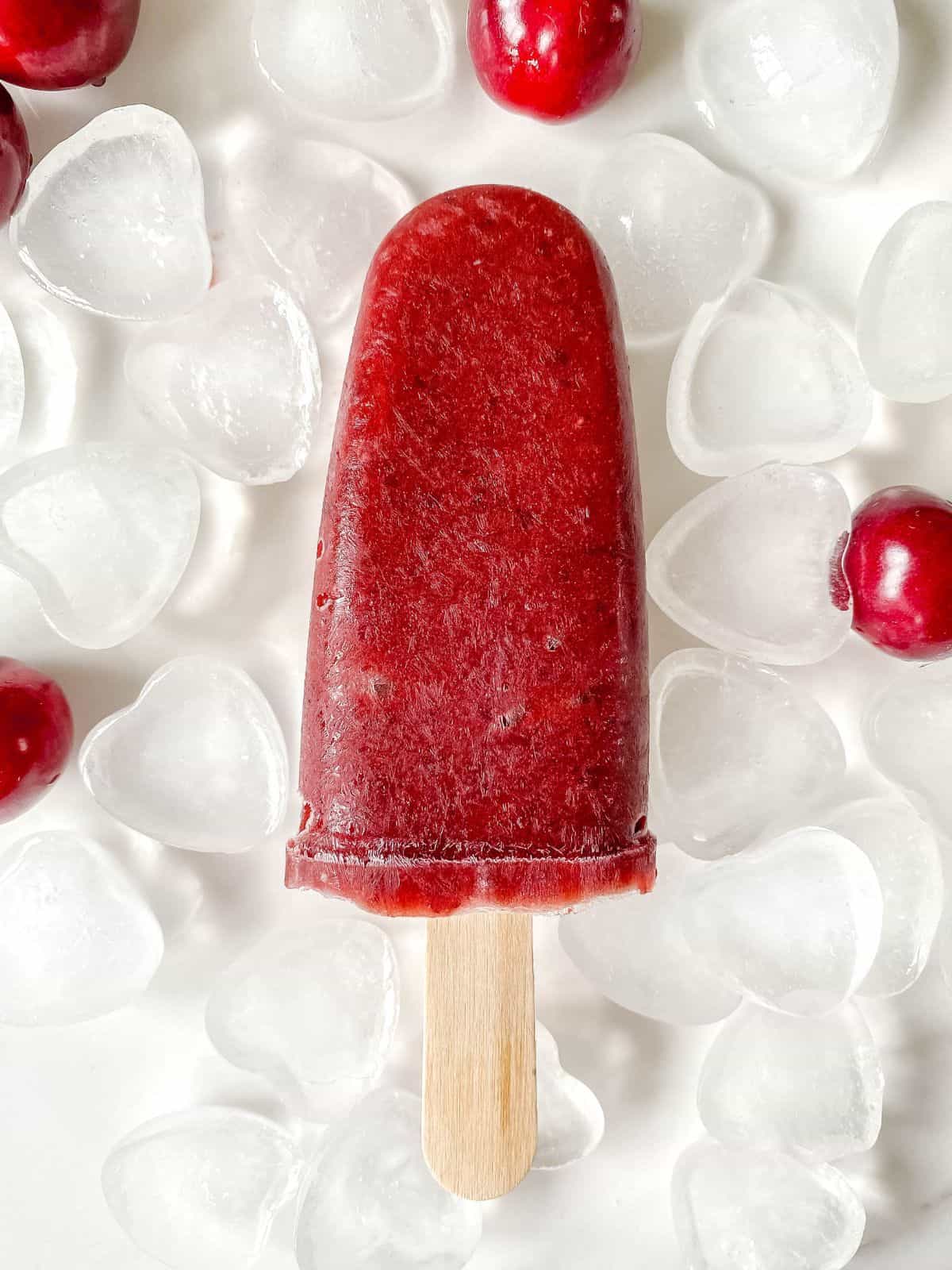 cherry mango popsicle on heart shaped ice with cherries.