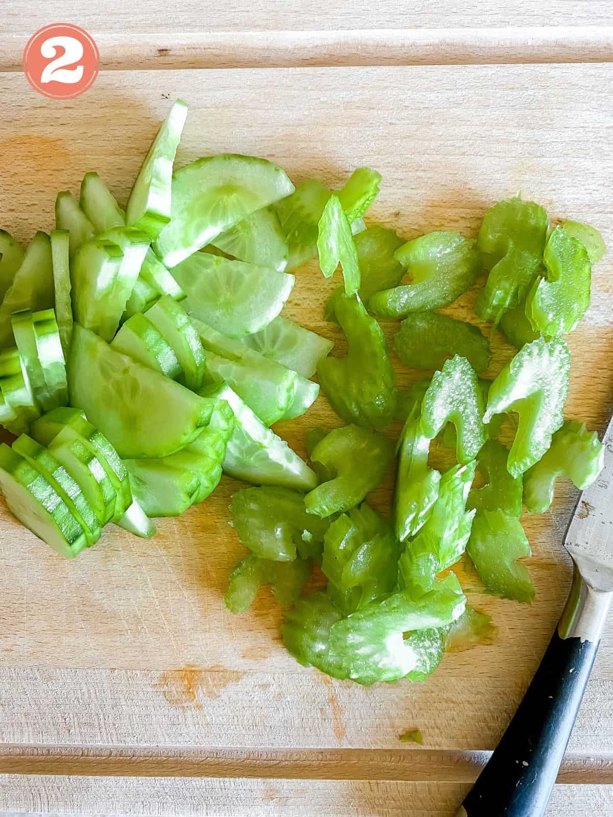 diced celery and cucumber on a wooden board.