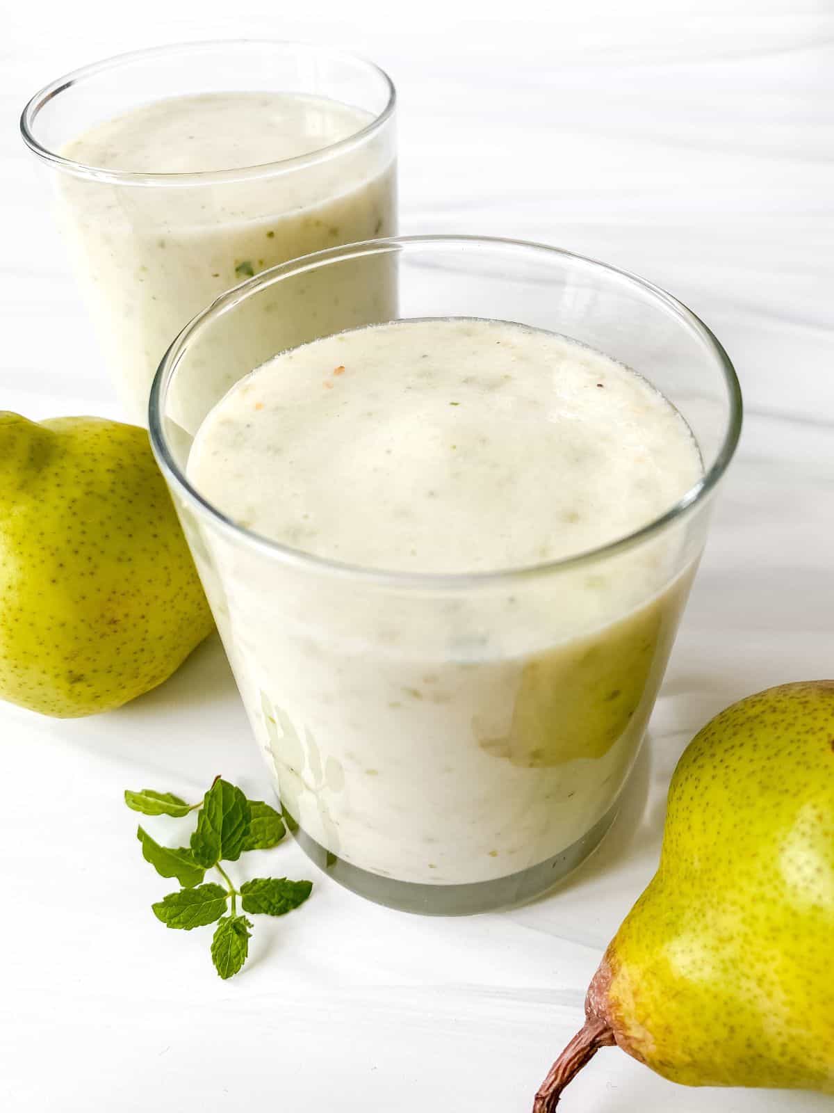 two glasses of lychee smoothie next to pears.