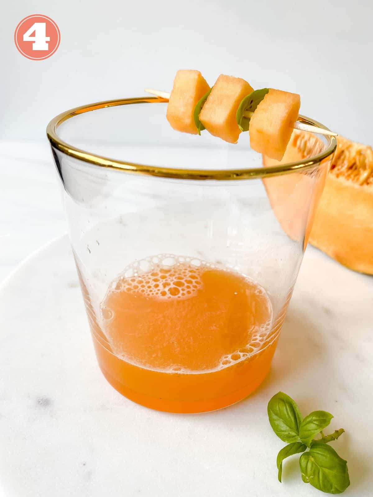 melon syrup in a glass with melon in the background.