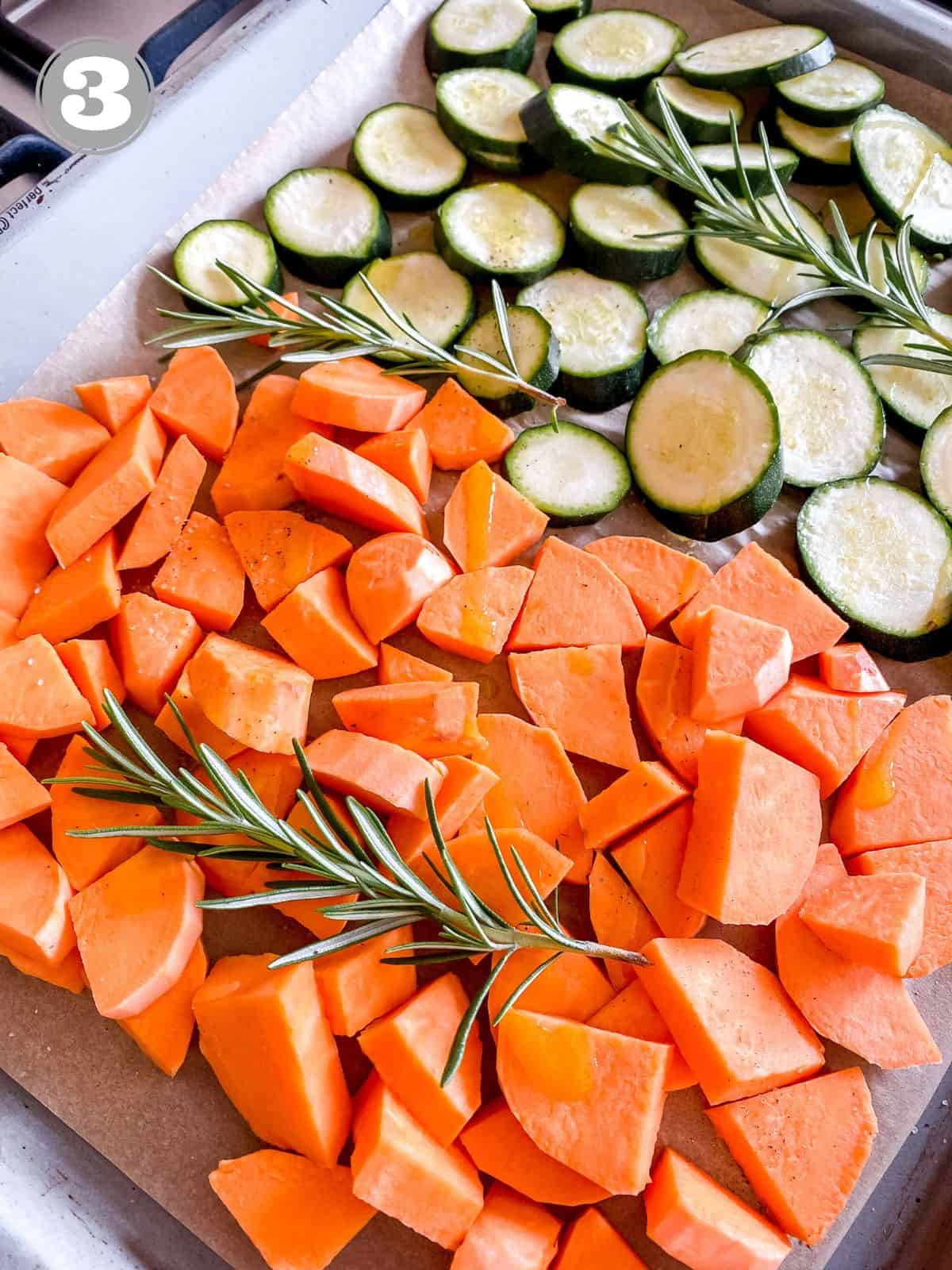 diced sweet potato, zucchini and rosemary on a lined baking tray.