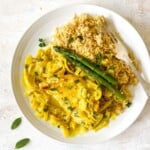 turkey with sage cream sauce on a plate with couscous and asparagus and a fork.