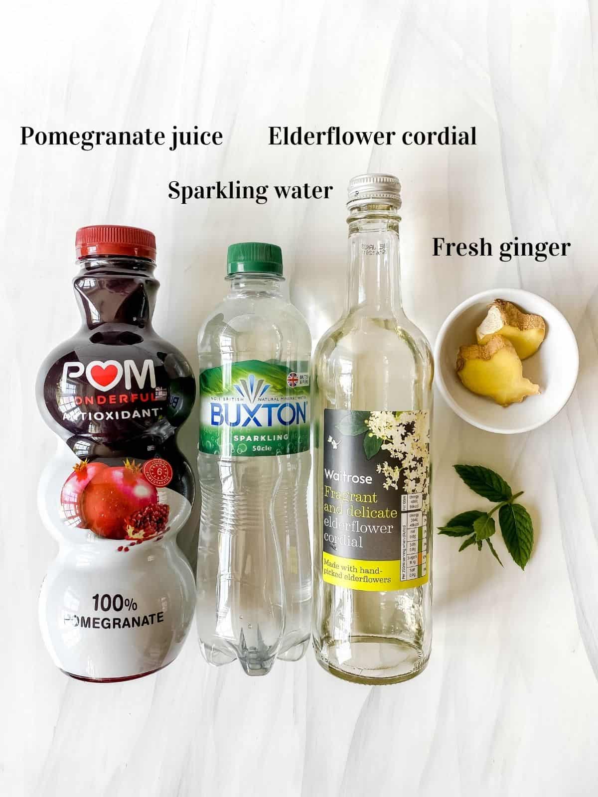 labelled bottles of pomegranate juice, sparkling water, elderflower cordial, fresh ginger and mint.