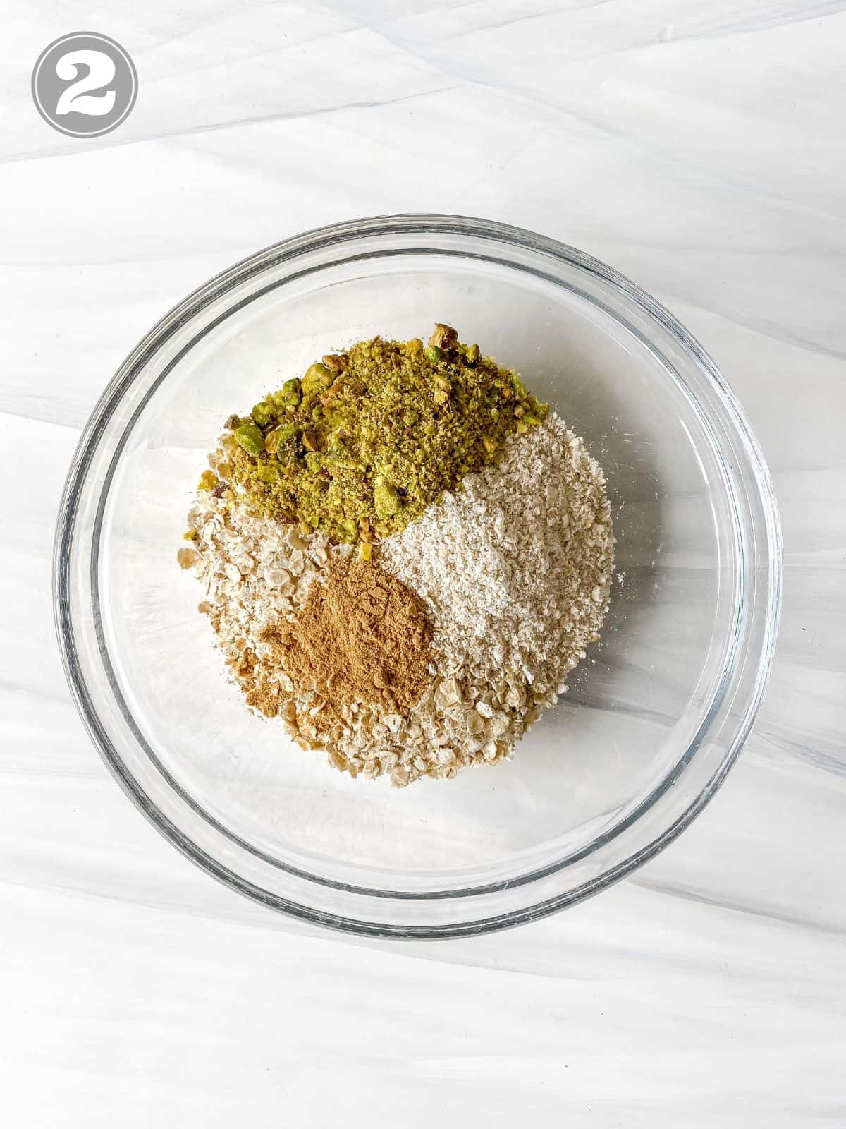 oats, ginger powder and pistachios in a glass bowl labelled number two.