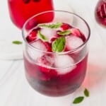 blackcurrant mocktail in a glass with mint and another glass in the background.