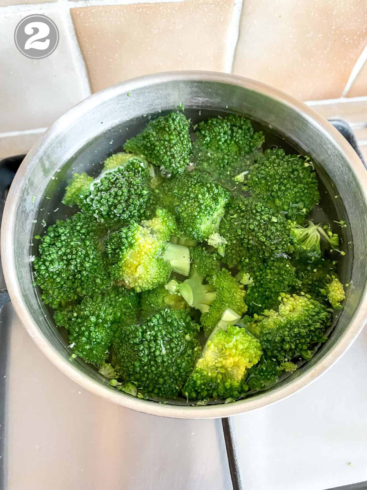 broccoli florets in a pan of water.