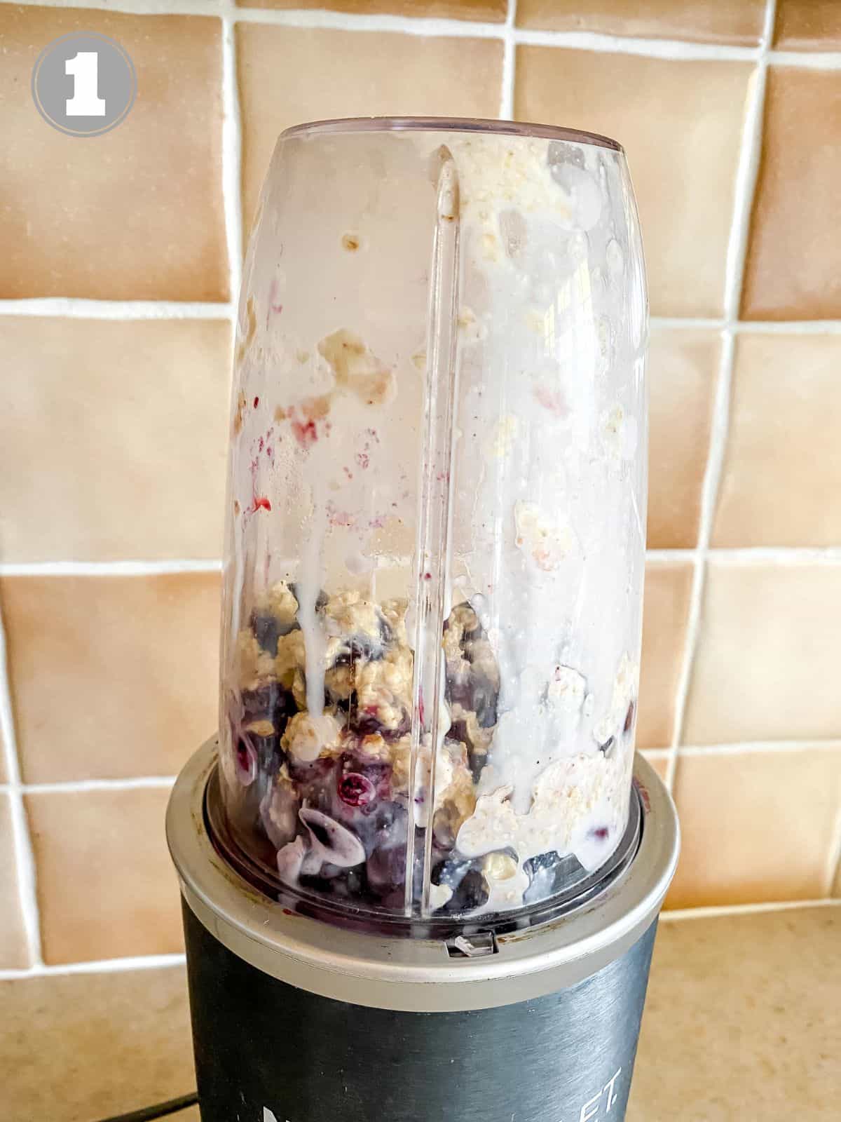 smoothie ingredients in a blender in front of a brown tiled wall.