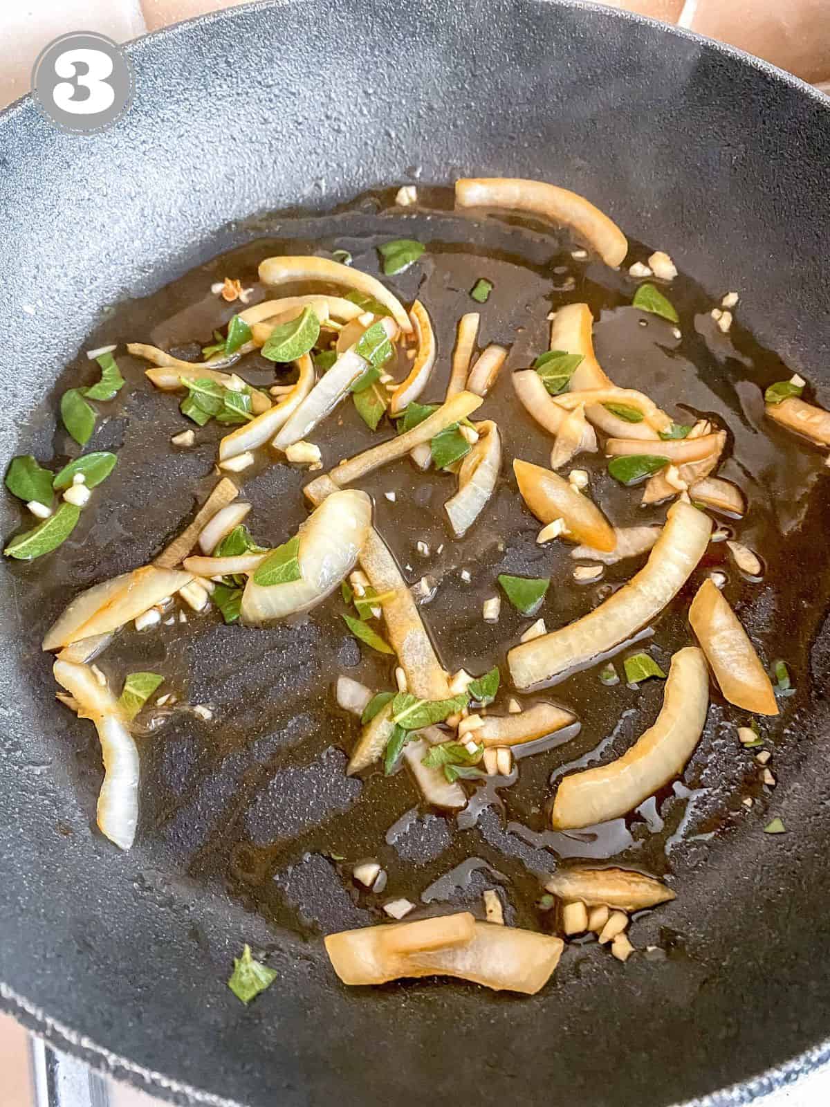 onion, garlic and sage leaves in chicken broth in a black skillet.