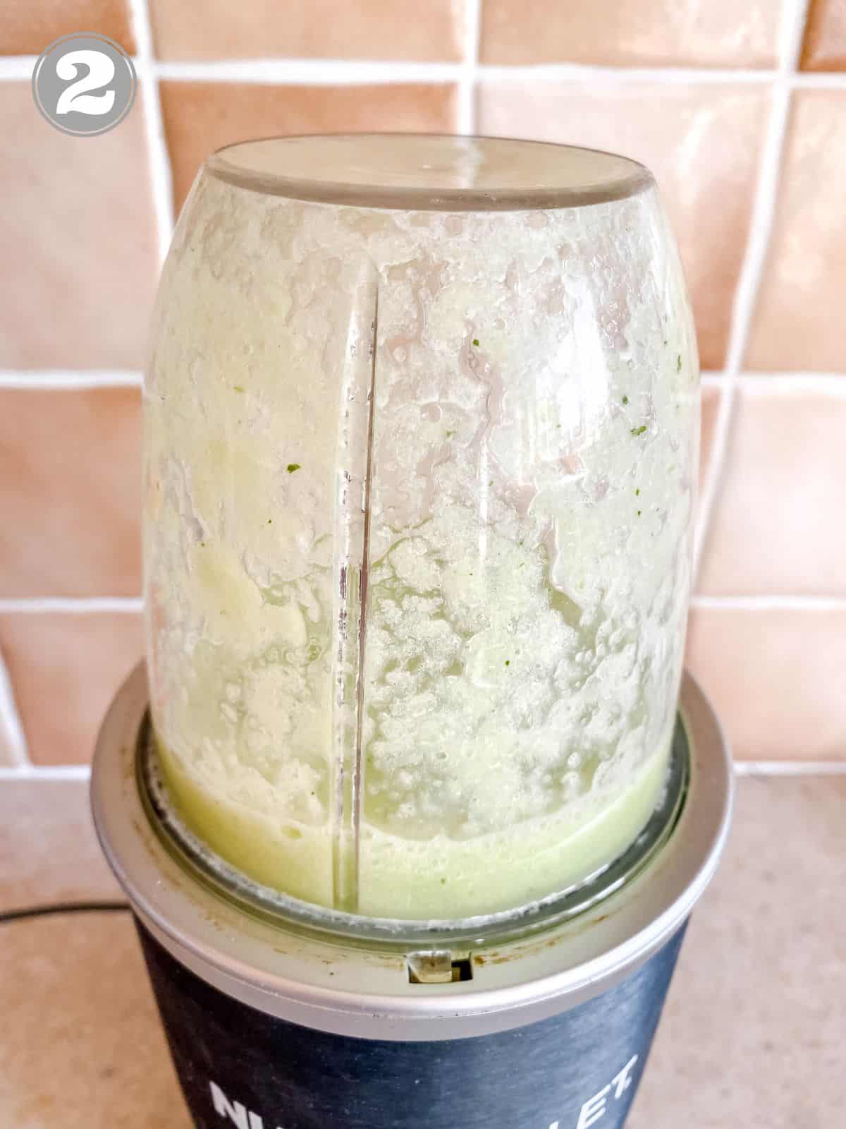 cucumber and mint in a blender against a brown tiled wall with number one in the corner.