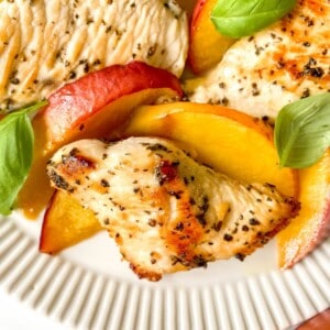 chicken, nectarines and basil leaves on a cream plate.