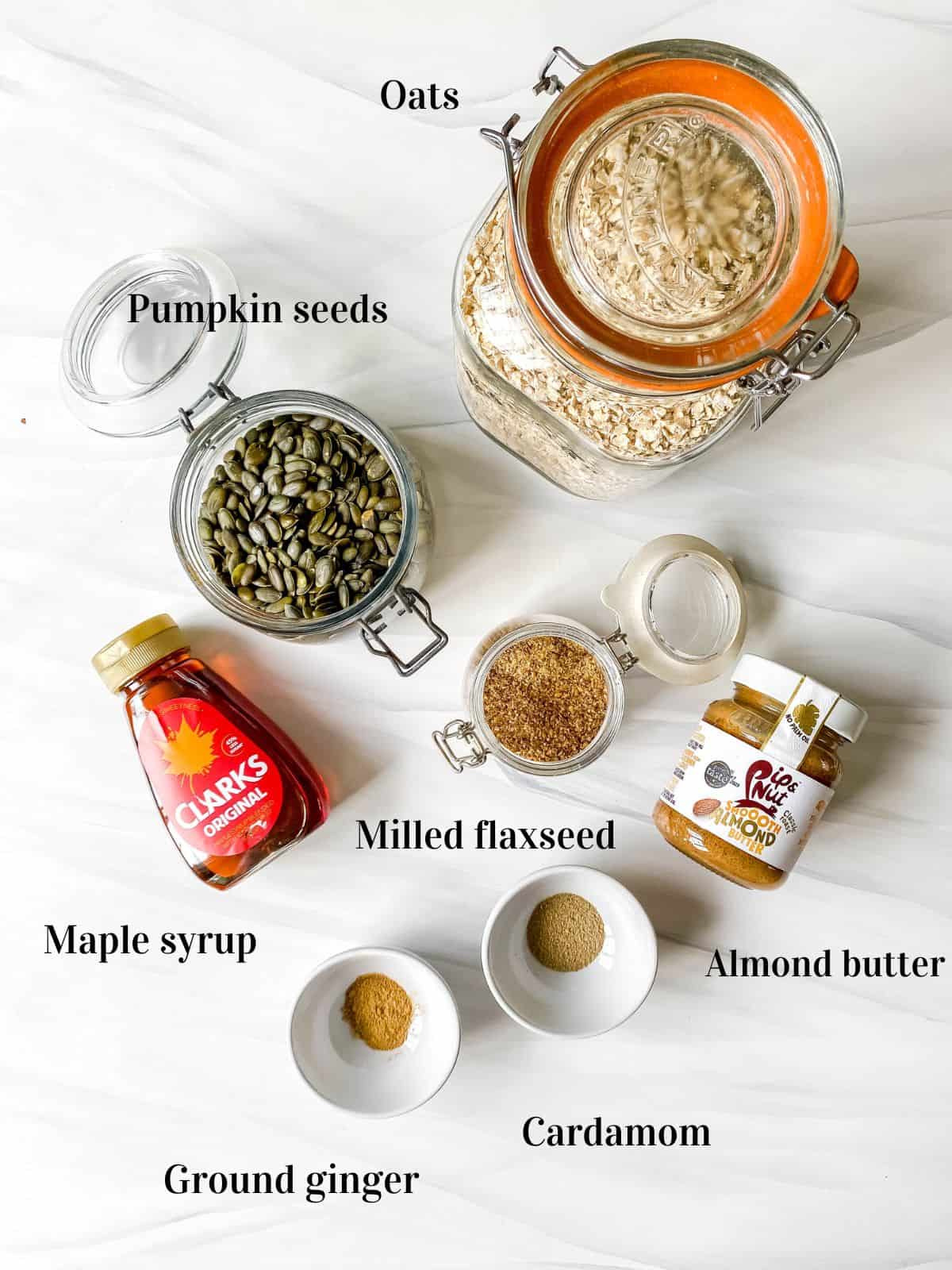 individually labelled ingredients to make cardamom oatmeal cookies including oats, maple syrup and pumpkin seeds.