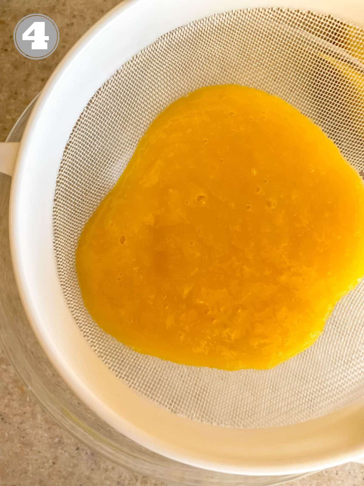 mango puree in a white sieve over a bowl labelled number four.