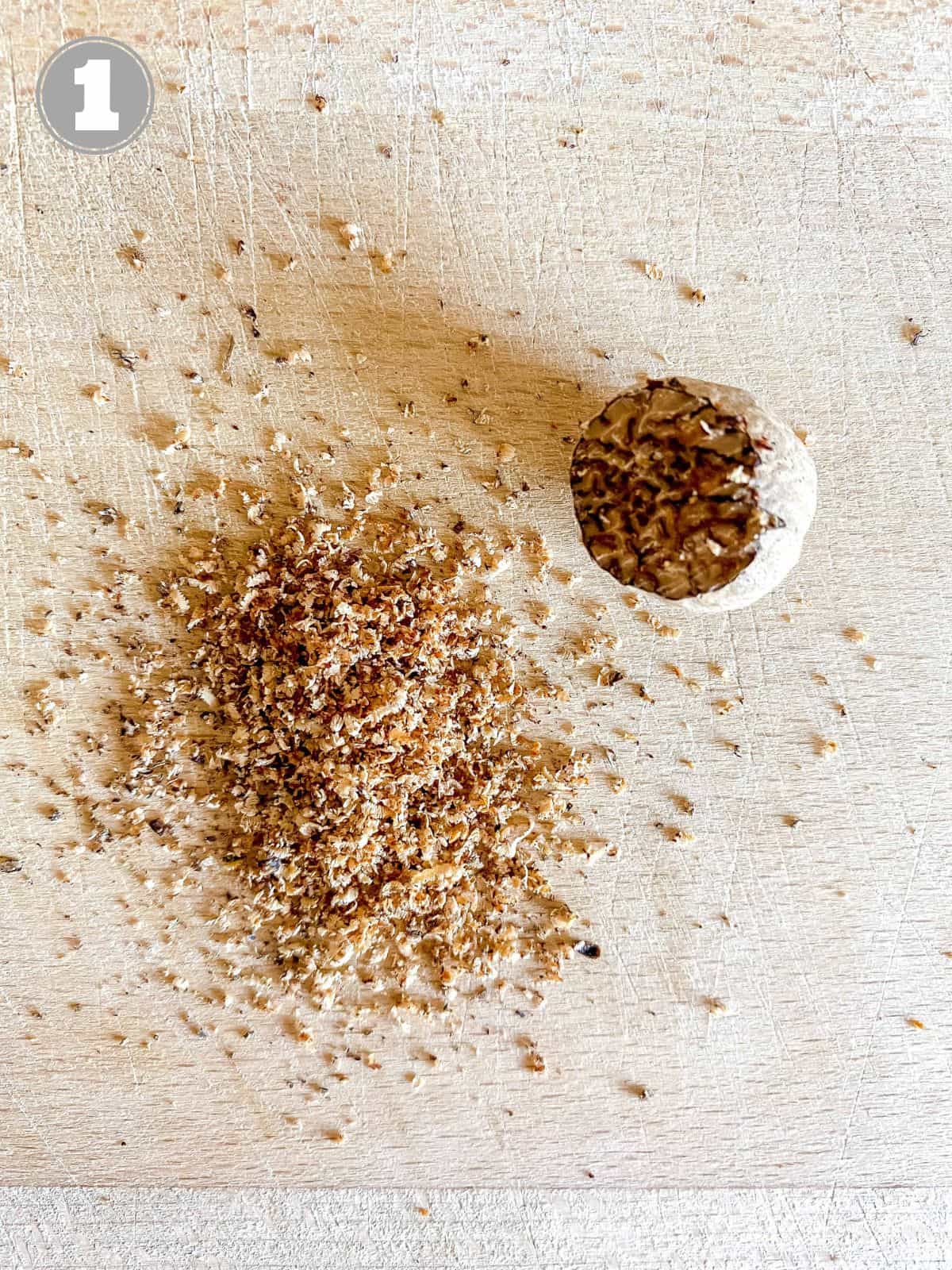 half a grated nutmeg on a wooden board labelled number one.