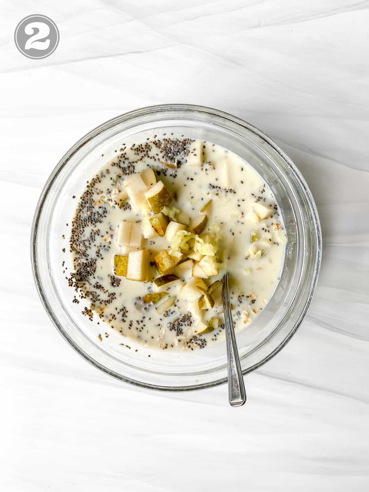 oats, pear, milk and chia seeds in a glass bowl with a spoon in it labelled number two.