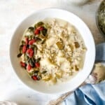 pear overnight oats in a white bowl on a blue cloth next to a decorative spoon.