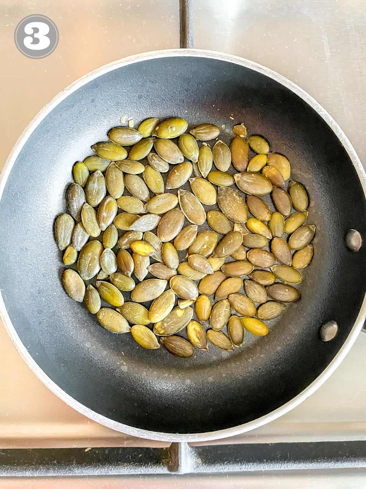 pumpkin seeds in a small black skillet labelled number three.