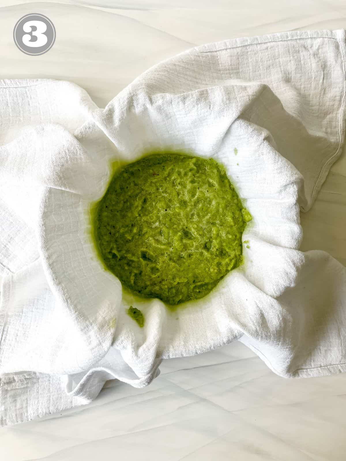 blended green vegetables in a muslin cloth over a bowl labelled number three.