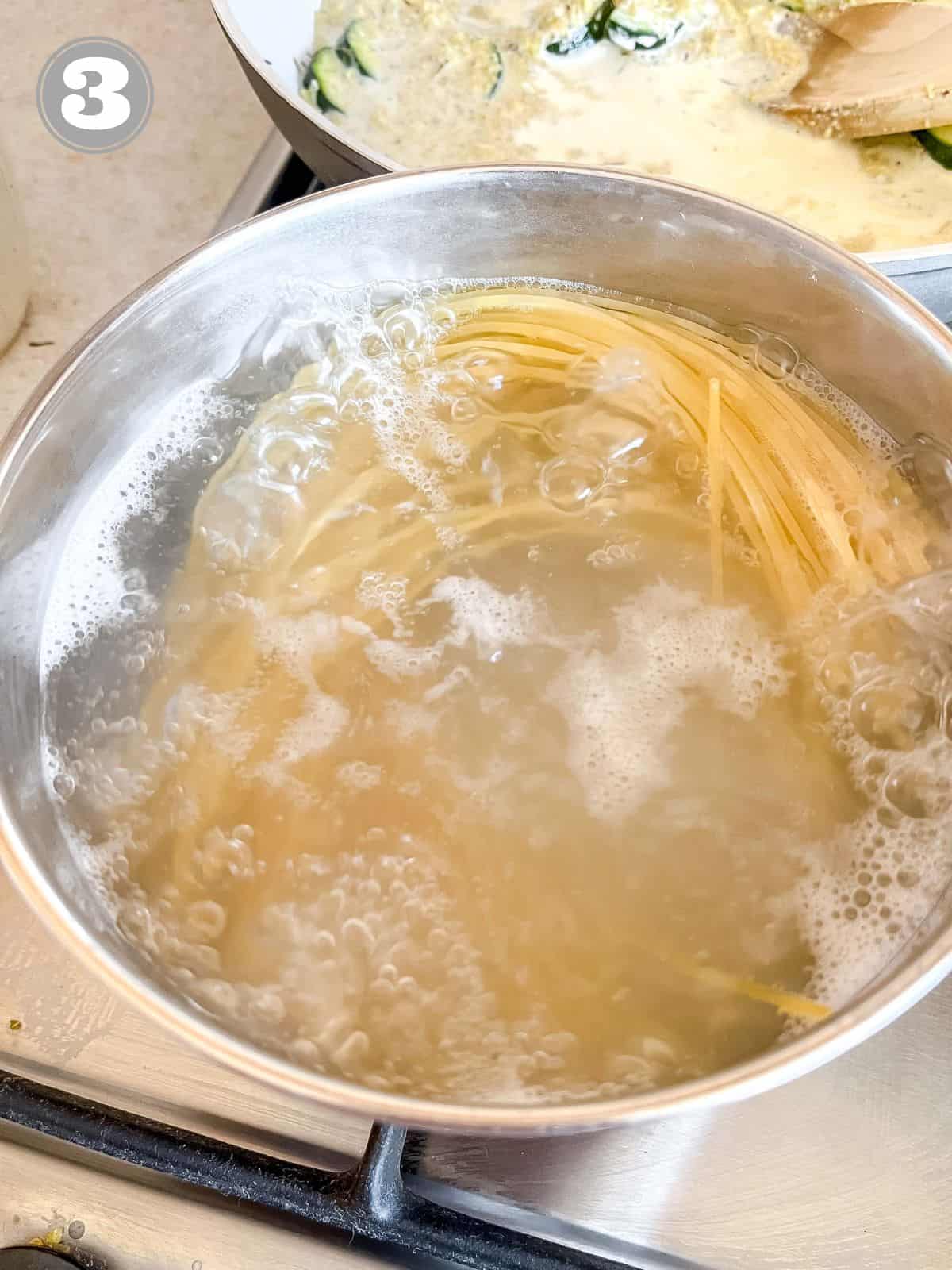 linguine in a pot of water with a skillet in the background labelled number three.