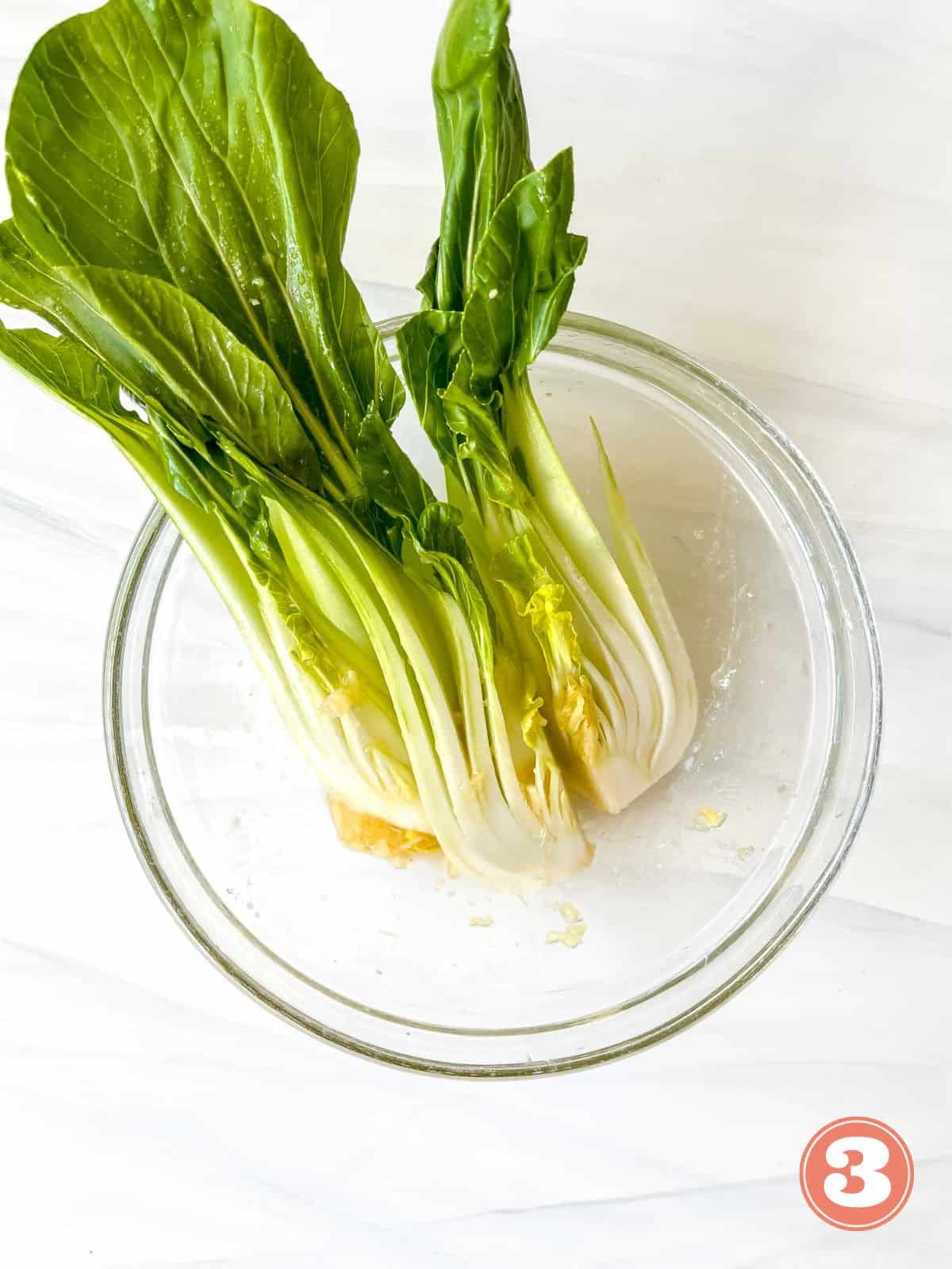 bok choy in a glass bowl with honey sesame dressing in labelled number three.