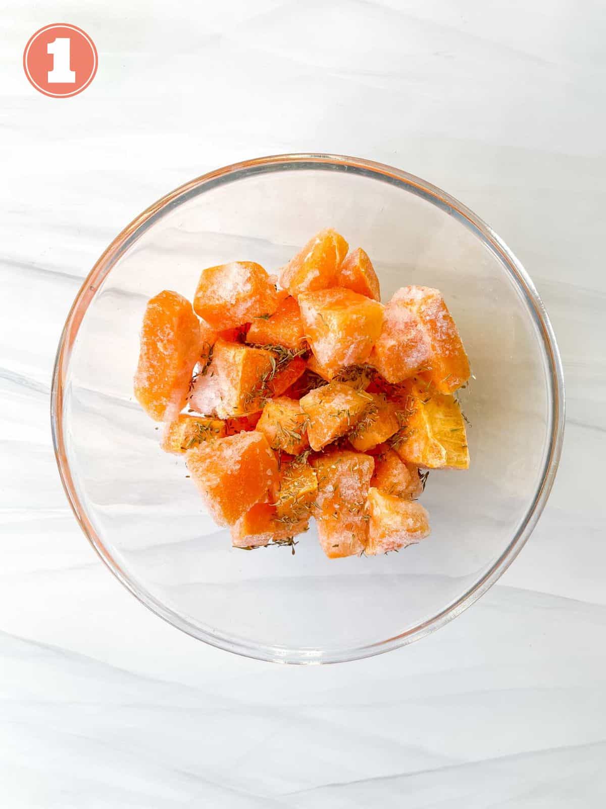 frozen butternut squash cubes in a bowl coated with oil and herbs labelled number one.