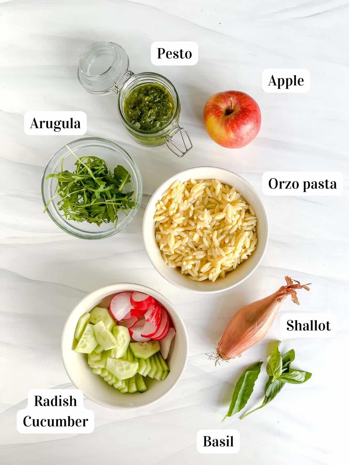 individually labelled ingredients to make pesto orzo salad including apple, radish, cucumber and basil.