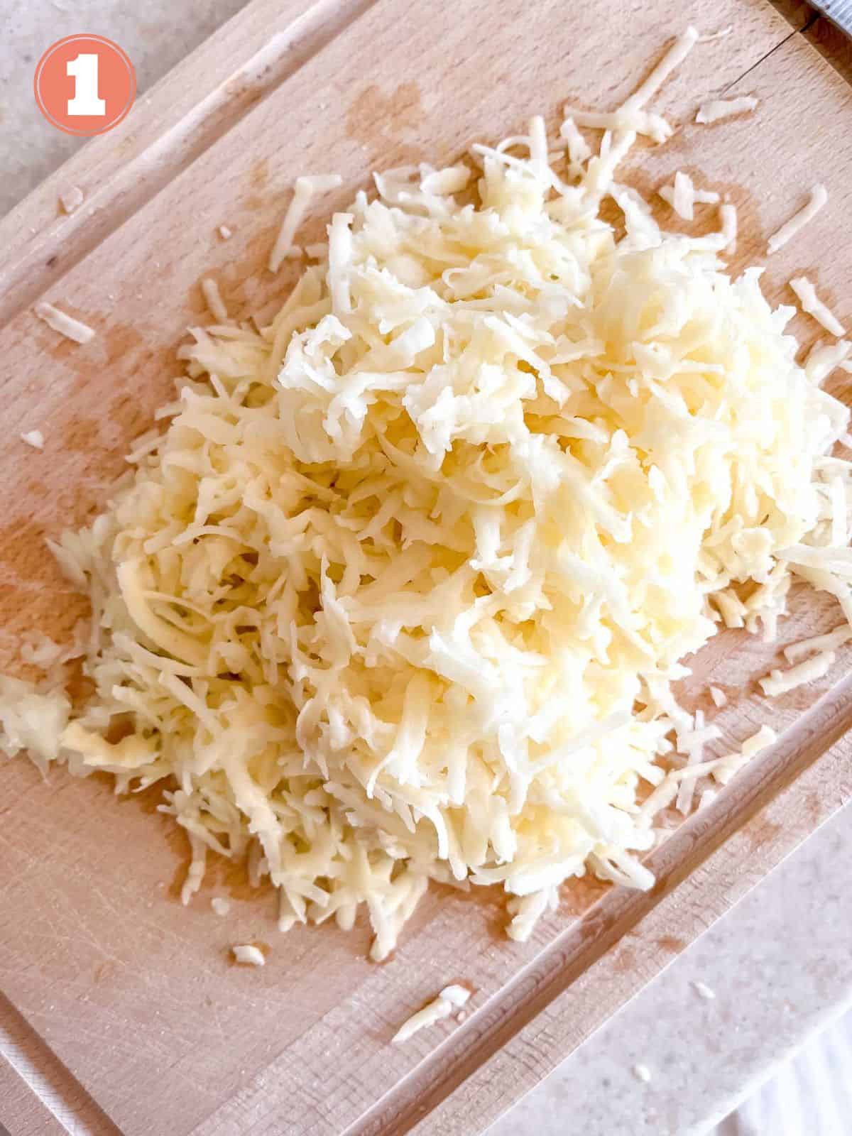 grated potato and onion on a wooden chopping board labelled number one.