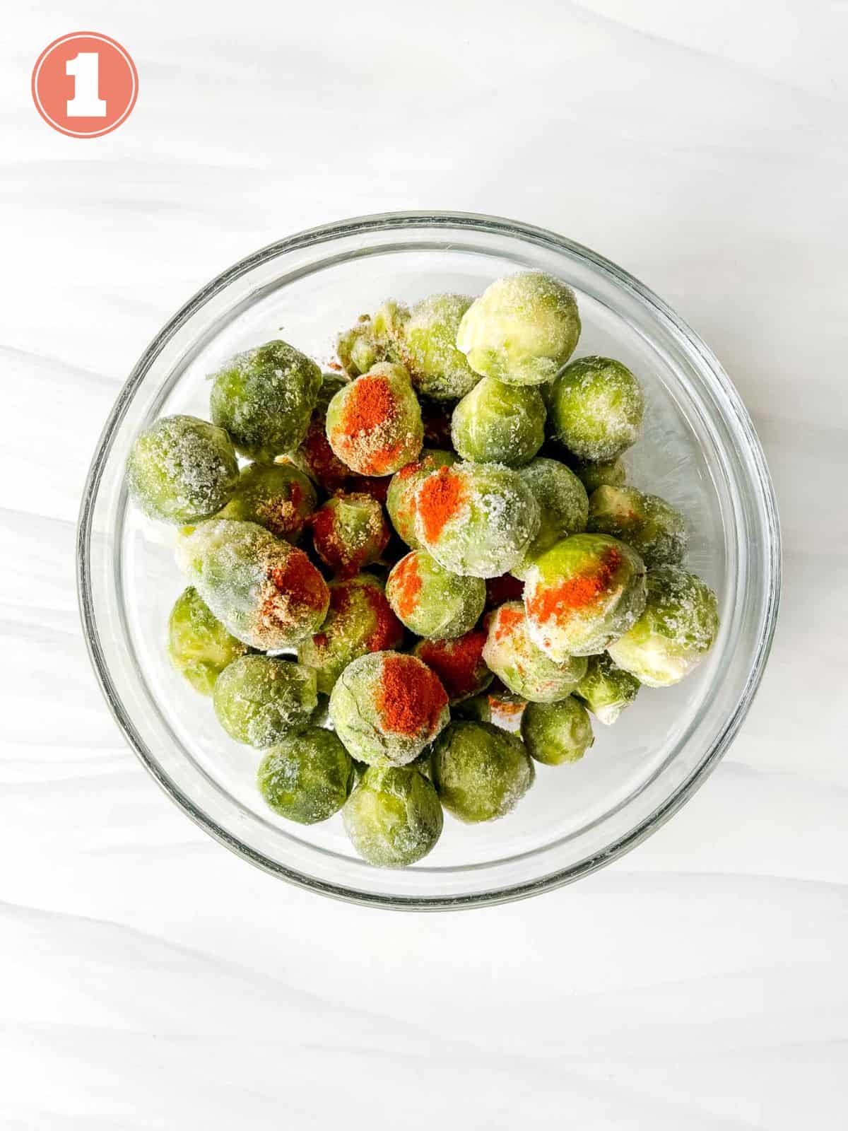 frozen Brussels sprouts with paprika sprinkled on them in a glass bowl labelled number one.