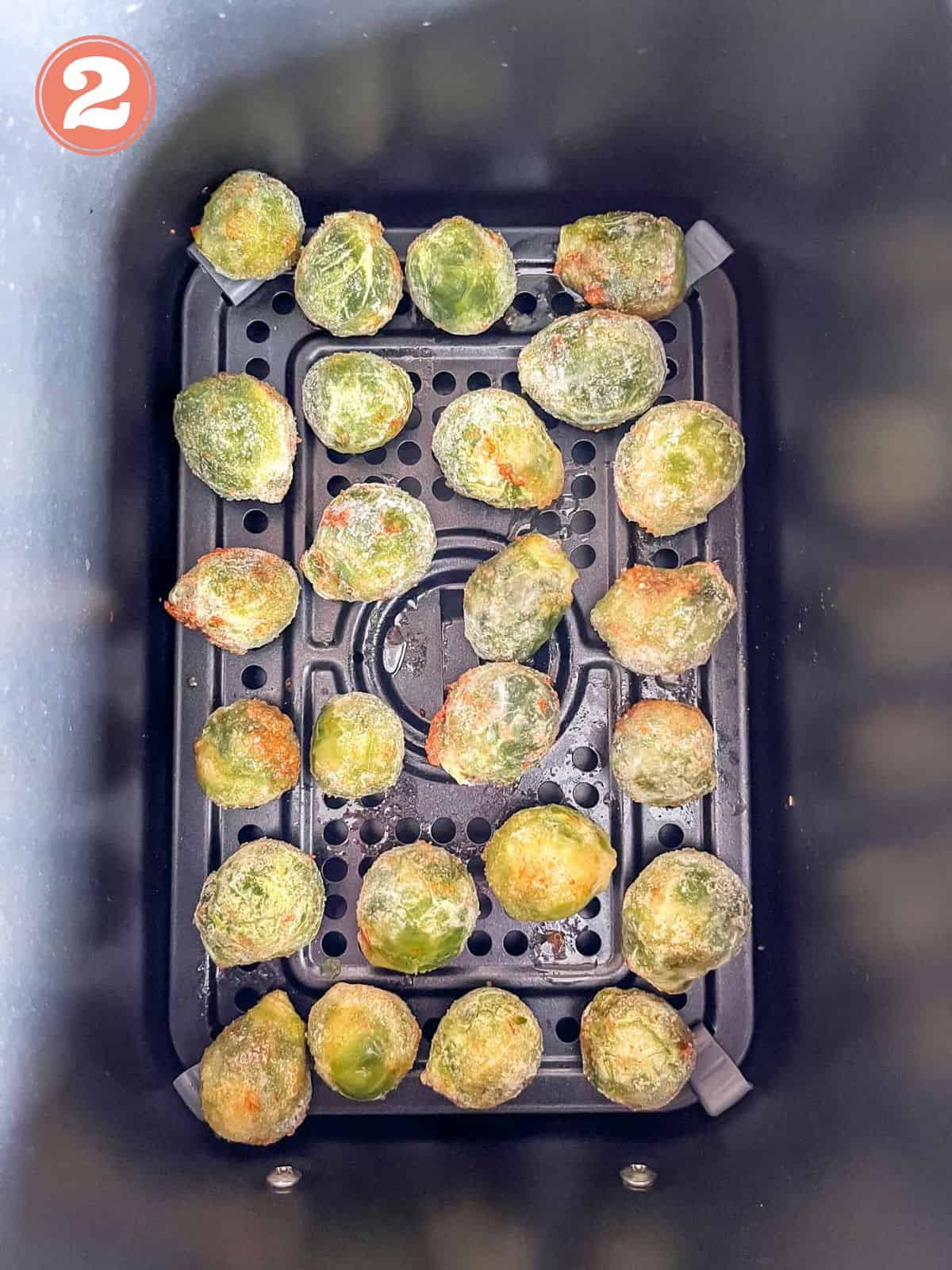 frozen Brussels sprouts in an air fryer basket labelled number two.