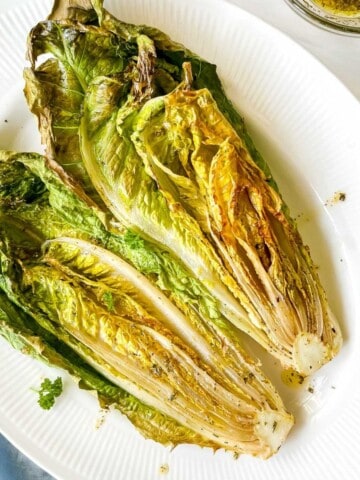 romaine lettuce halves on a white plate on a blue cloth.