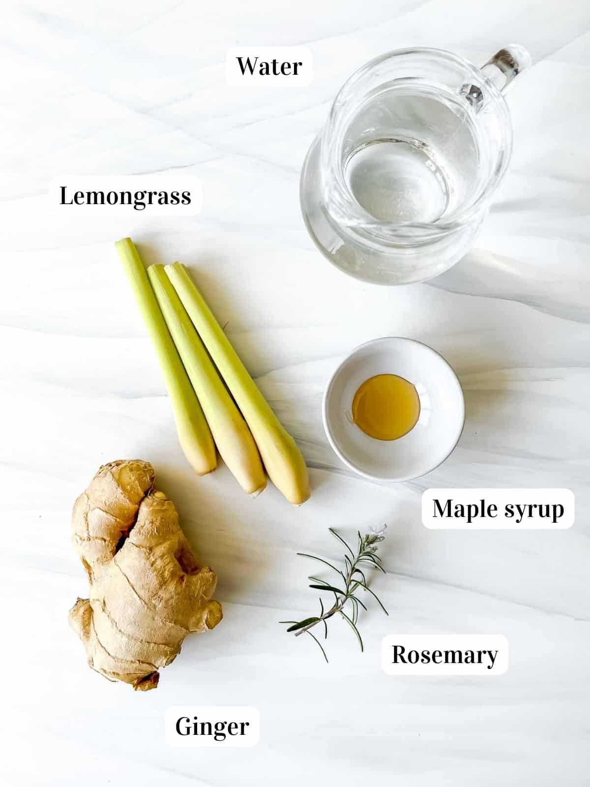 labelled lemongrass stalks, ginger, jug of water, rosemary and bowl of maple syrup.