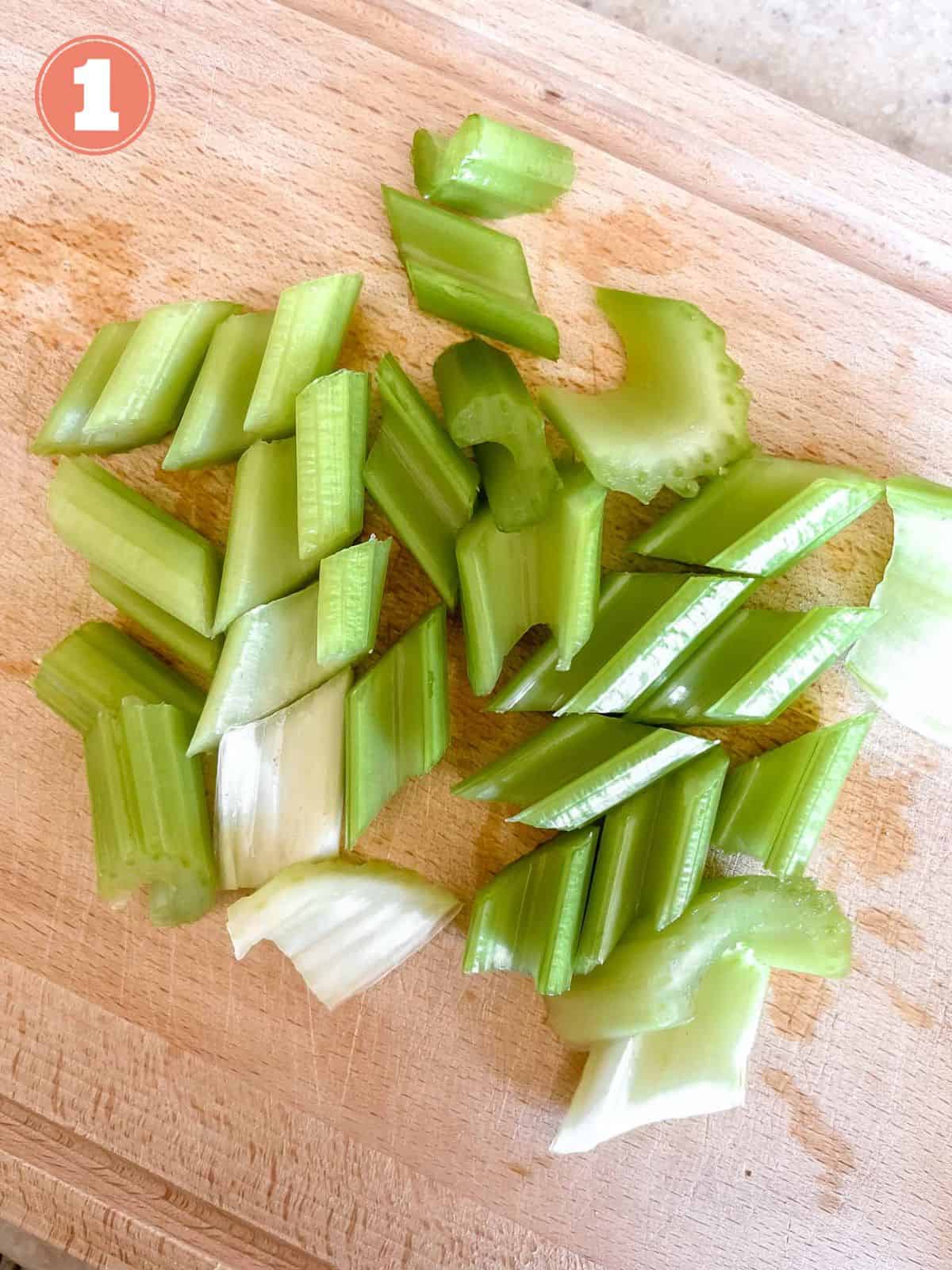 diced celery on a wooden chopping board labelled number one.