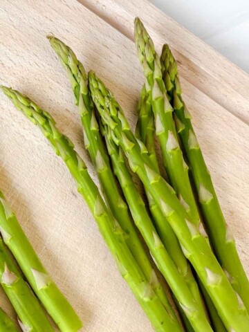 asparagus spears on a wooden chopping board.