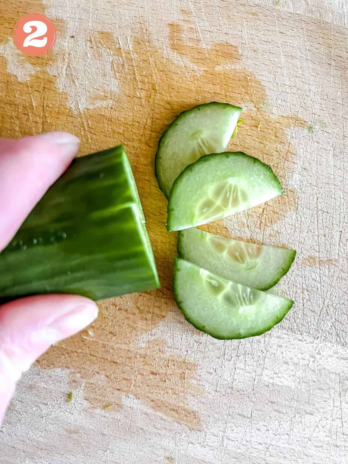 sliced cucumber on a wooden chopping board labelled number two.