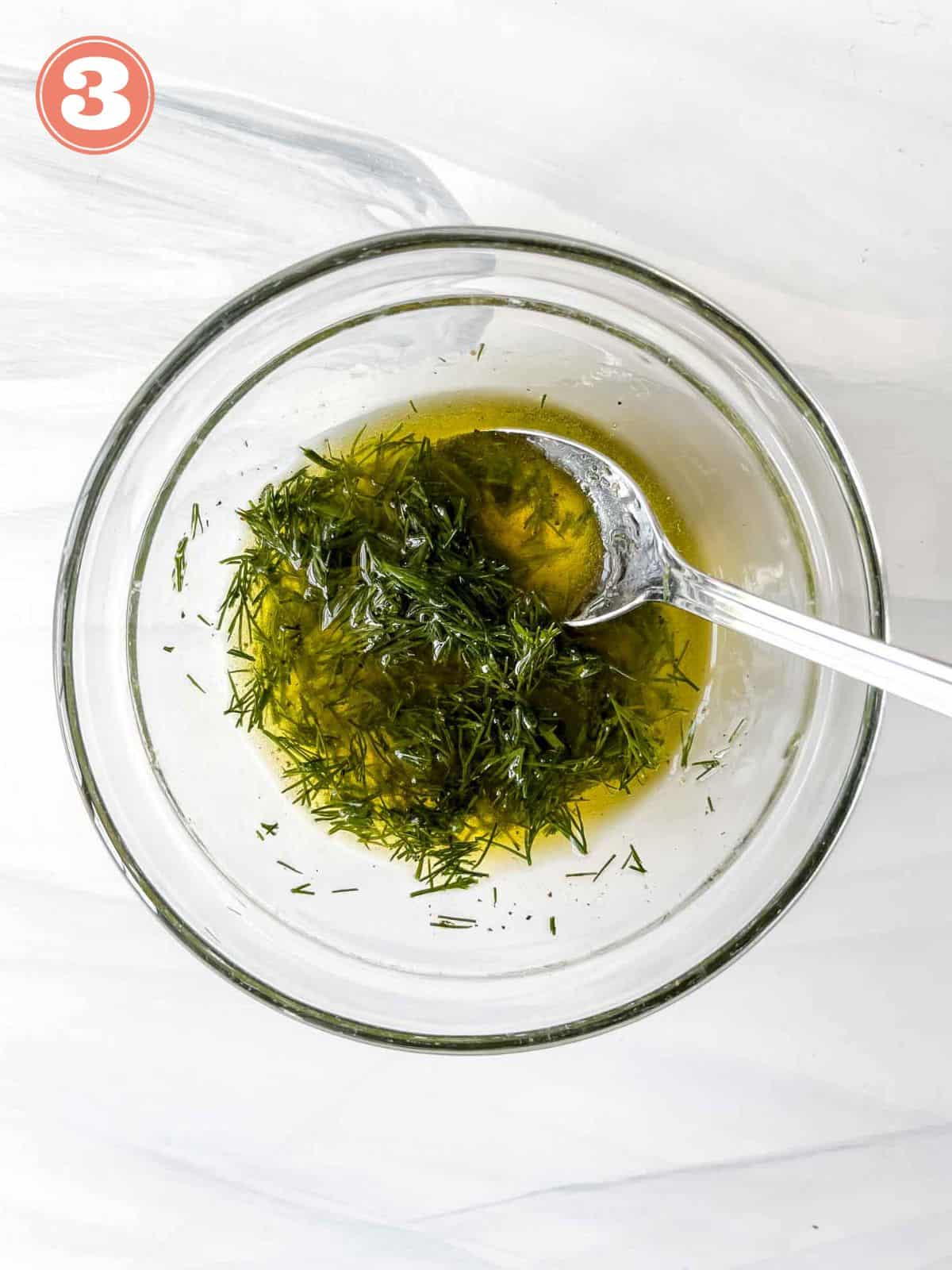 olive oil dill salad dressing in a glass bowl with a spoon in it labelled number three.