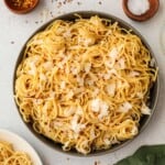 cream cheese pasta in a black bowl next to small wooden bowls of salt and peppercorns.