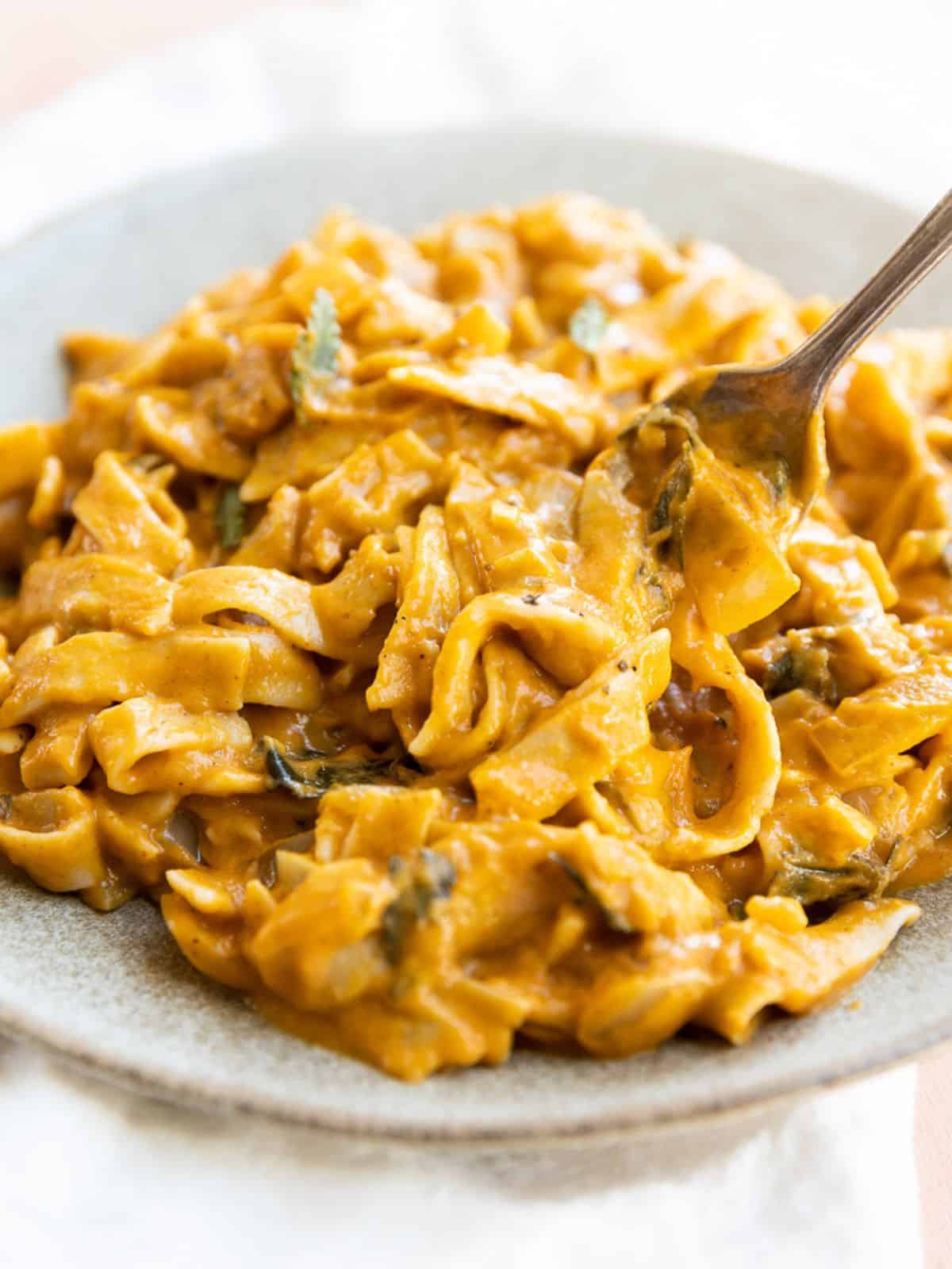 pumpkin pasta sauce recipe in a light grey bowl with a fork in it.
