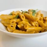 sweet potato pasta sauce recipe in a white bowl with sage leaves.