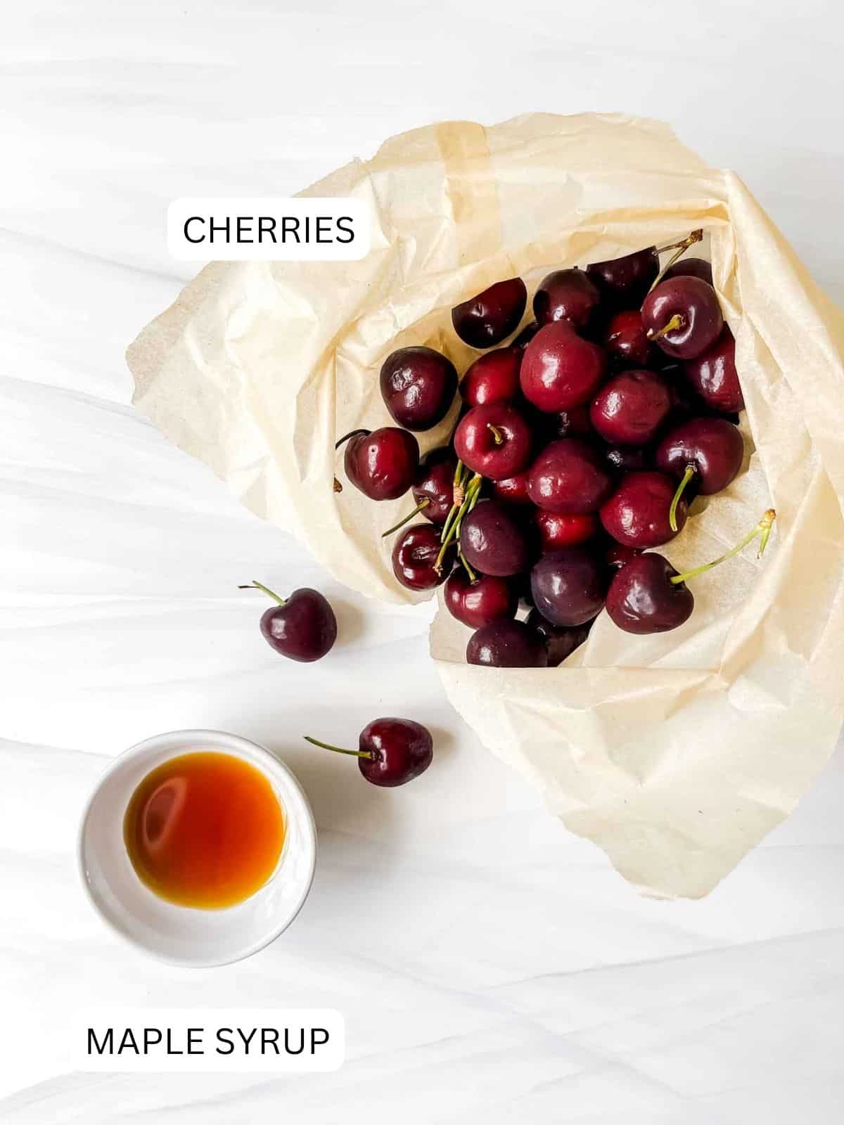 labelled cherries in a brown paper bag and maple syrup in a small white bowl.