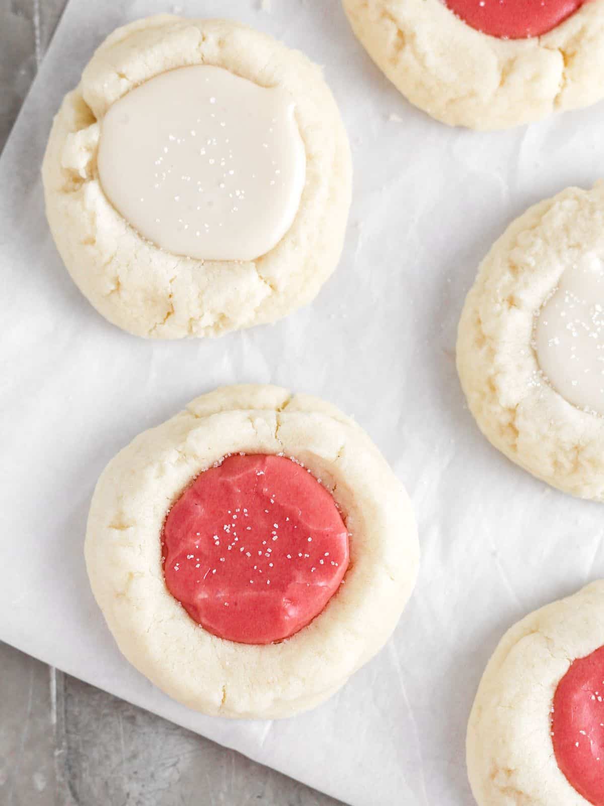 pink and white thumbprint cookies on parchment paper.